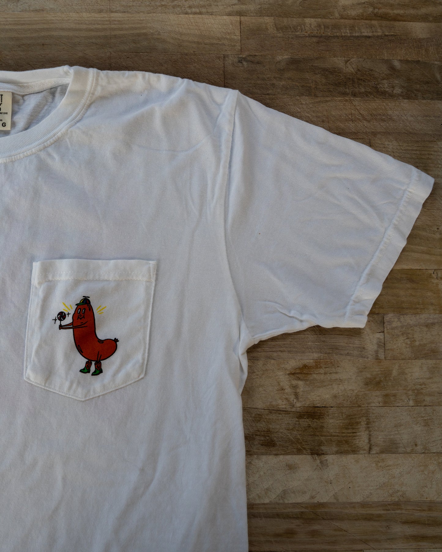 White t-shirt with a red cartoon character on a wooden surface